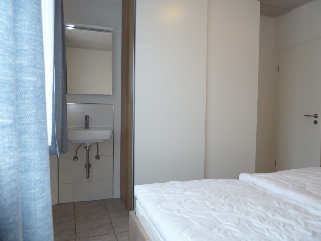 Schalfzimmer mit großem Kleiderschrank und Waschbecken und Spiegelschrank